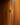 Close-up of a wooden cabinet door with a brass vertical height adjustment strip and a metal hinge.